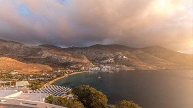 Panorama, Amorgos adasında gün batımında turuncu bulutları gösteriyor. Geleneksel Yunanistan - tepelerde beyaz evler ve turkuaz deniz, Kiklad