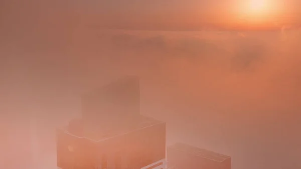 stock image Sunrise over rare early morning winter fog above the Dubai Marina skyline and skyscrapers lighted by orage sun light aerial . Top view from above clouds. Dubai, UAE