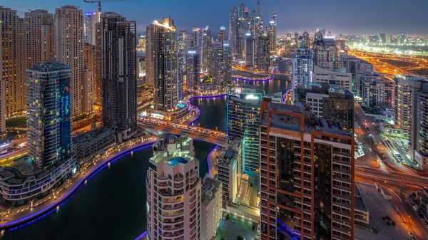 View of various skyscrapers in tallest recidential block in Dubai Marina aerial day to night transition  with artificial canal and bridges over it. Many towers and yachts after sunset