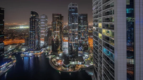 Panorama showing tall residential buildings at JLT district aerial night , part of the Dubai multi commodities centre mixed-use district. Illuminated towers and skyscrapers