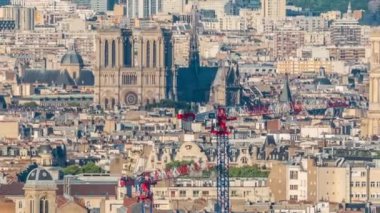 Paris 'teki evlerin çatılarının üstündeki hava manzarası. Notre Dame de Paris ve Saint-Sulpice 'in akşam manzarası günbatımını besliyordu. İnşaat alanındaki vinçler