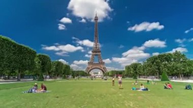Paris 'teki Champs de Mars' taki Eyfel Kulesi. Zaman atlaması, Fransa. Yazın mavi bulutlu gökyüzü yeşil çimlerle kaplı ve insanlar etrafta dolaşıyor. İlerliyorum.