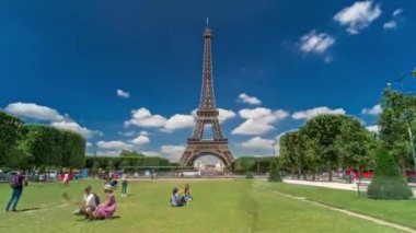 Paris 'teki Champs de Mars' taki Eyfel Kulesi. Zaman atlaması, Fransa. Yazın mavi bulutlu gökyüzü Yeşil çimlerle ve insanlar etrafta yürüyüp rahatlıyorlar