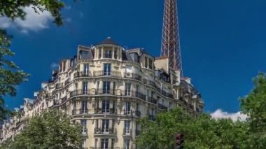 Paris 'teki tarihi binaların arkasında Eyfel Kulesi. Zaman atlaması, Fransa. Yazın mavi bulutlu gökyüzü Yeşil ağaçlar ve caddelerde trafik