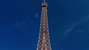 Eiffel Kulesi Paris 'teki Siene Nehri üzerindeki köprüden görüldü. Zaman atlaması, Fransa. Yazın mavi bulutlu gökyüzü Yeşil ağaçlar ve etrafta yürüyen insanlar