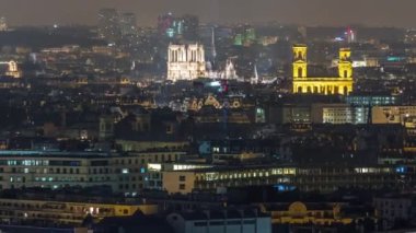 Paris 'te bir gece vakti çatıların üstündeki hava manzarası. Aydınlatılmış Notre Dame de Paris ve Saint-Sulpice katedrali manzaralı. Işıklar sönüyor.