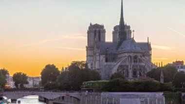 Aydınlatılmış Notre Dame De Paris katedralinin arka görüntüsü gün batımından sonra gece geçiş zamanı. Tournelle Köprüsü 'nden rıhtıma görüntü. Arka planda turuncu gökyüzü. Paris, Fransa, Avrupa.