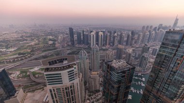 Dubai Marina Panorama 'sı JLT gökdelenleri ve golf sahası zaman çizelgesiyle gün batımında, Dubai, Birleşik Arap Emirlikleri. Yukarıdaki kulelerden hava görüntüsü. Bulanık hava ile şehir silüeti