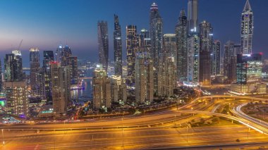 Dubai Marina 'nın gökdelenleri gün batımından sonra gün batımından sonra trafik varken gece gündüz en yüksek konut binaları aydınlatılıyor. JLT bölgesinden hava üst görünümü