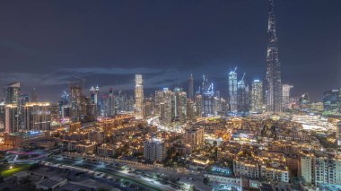 Dubai şehir merkezi panorama gece gündüz geçiş zamanı en yüksek gökdelen ve diğer kule manzaralı Dubai, Birleşik Arap Emirlikleri gün batımından sonra tepeden. Işıklar yanıyor..
