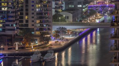 Dubai marinası rıhtımda gece vakti hava kanalı boyunca gezinti yaptı. Dubai 'nin modern yerleşim bölgesinde köprü trafiği var.