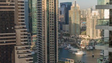 Dubai Marina gökdelenlerindeki hava manzarası ve liman zamanındaki en lüks yat. Akşamları uzun gölgeli kuleler rıhtım boyunca yürüme alanı boyunca. Dubai, Birleşik Arap Emirlikleri
