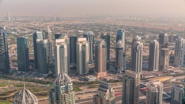 Dubai marina kuleleri ve JLT bölgesi. Şeyh Zayed yolu üzerinde metro istasyonunun yakınındaki trafik. Gölgeler hızla ilerliyor. Yukarıdan aşağıya bak, gökdelenler çatılar, Birleşik Arap Emirlikleri.