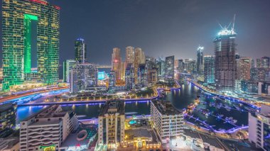 Dubai Marina Panorama 'sında limana park etmiş birkaç tekne ve yatlar ve kanal havası çevresindeki gökdelenler gece geçiş zamanına dönüşüyor. Arka planda JBR bölgesi kuleleri