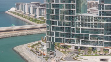 Gezinti güvertesi ve Dubai şehir manzarası Dubai marinasından gölgeler hızla hareket ederken görülüyor. JBR bölgesi ve Bluewater Adası 'nın arkasında oteller ve gökdelenler var..