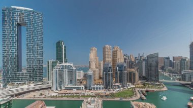 Dubai Marina Panorama 'sında limana park etmiş birkaç tekne ve yatlar ve kanalın etrafında gölgeli gökdelenler var. Arka planda JBR bölgesi kuleleri