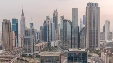 Dubai Finansal Merkezi 'nin panoraması. Gece gündüz aydınlatma saatleri olan yüksek gökdelenleri var. Gün doğmadan önce yoğun karayolu boyunca kulelerin hava görüntüsü