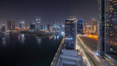 Panorama Dubai Business Bay 'deki gökdelenleri gösteriyor. Su kanalı gece zaman ayarlı. Aydınlatılmış kuleleri ve rıhtımı olan modern gökyüzü. Uluslararası bir iş merkezi.