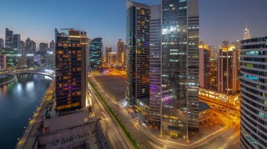 Dubai Business Bay 'deki ve şehir merkezindeki gökdelenlerin şehir manzarası ve su kanalları gece zaman çizelgesi. Günbatımından sonra kuleleri ve rıhtımı olan modern gökyüzü. Uluslararası bir iş merkezi.