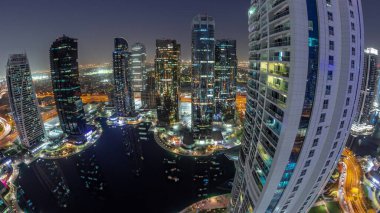 Dubai çok amaçlı emtia merkezi karma kullanım bölgesinin bir parçası olan JLT bölge hava sahasındaki panorama binalarından gece geçiş zamanına kadar. Göl kenarındaki gökdelenler