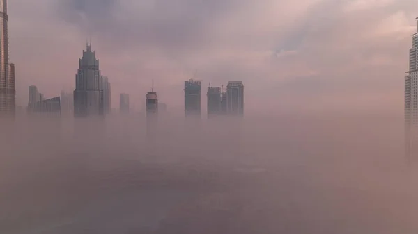 空中からの眺め朝の霧がドバイ国際金融センター地区のタイムラプスを覆いました 日の出の間に近代的な高層ビルやモールがあるオフィスタワーとホテル — ストック写真
