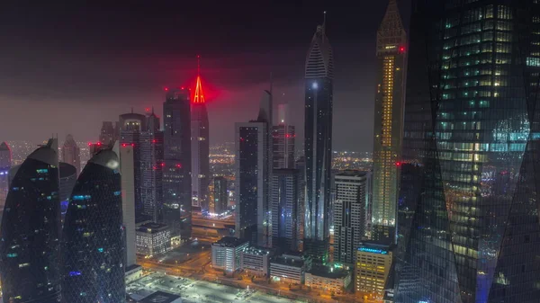 夜のタイムラプス ドバイ アラブ首長国連邦中の豪華な高層ビルが点在するドバイ市の金融センター 霧に覆われた駐車場や塔の屋根と空中ビュー 明かりが消える — ストック写真