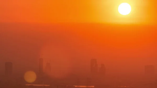 緑の上に日の出とドバイマリーナからのアルバーシャの高さ地区の航空時間経過 上からゴルフ場近くのタワーや高層ビルの後ろに昇る太陽 — ストック写真