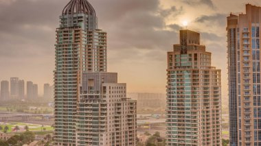 Dubai Marina üzerinde gündoğumu lüks turizm bölgesi. Kanal anteninin etrafında gökdelenler ve kuleler var. Residential binalar ve caddelerdeki trafik. Turuncu bulutlar