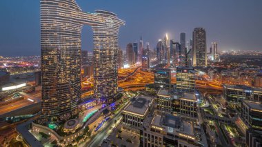 Fütürist Dubai Şehir Merkezi ve finans bölgesi gökyüzü gününden geceye geçiş. Birçok aydınlık kule ve gökdelenler caddelerde trafik var.