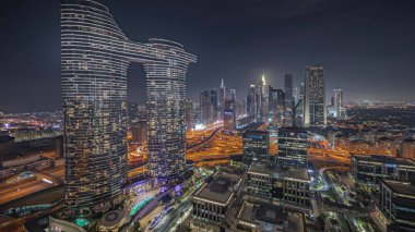 Panorama showing futuristic Dubai Downtown and finansial district skyline aerial night . Many illuminated towers and skyscrapers with traffic on streets