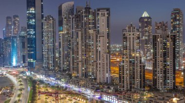 Business Bay hava sahasında modern kuleleri olan körfez bulvarı, gündüzden geceye geçiş, Dubai, BAE. Gün batımından sonra gökdelenler