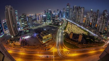 Panoramic skyline of Bay Avenue with modern towers residential development in Business Bay aerial day to night transition , Dubai, UAE. Skyscrapers with traffic on a road near big parking lot