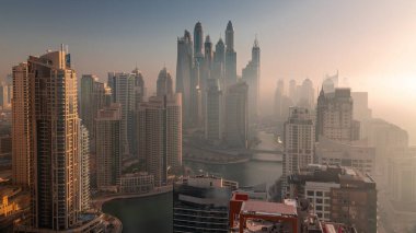 Dubai Marina 'nın en yüksek karşılama bloğundaki çeşitli gökdelenlerin suni kanallı gündoğumu sırasında görüntüsü. Birçok kule ve yat sisli sabahın erken saatlerinde