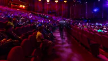 Seyirciler konser salonunda toplanıp gösteriyi zaman aşımına uğratarak izliyorlar. Kırmızı koltuklu büyük bir salon. Işığı kapatana kadar izleyiciler yerlerini dolduruyor. Sol taraftan panoramik görünüm
