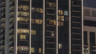 Şehrin hava zaman ayarlı yerleşim bölgesinde parlayan pencereleri olan uzun apartmanlar. Kulelerin ve gökdelenlerin tepesindeki odalarda akşam ışığı