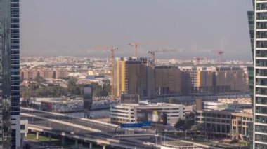 Dubai su kanalı çevresindeki inşaat alanında birçok vinç havadan zaman ayarlı. Evler ve villalar arkada. Sabah köprüde trafik vardı. Uzun gölgeler vardı.