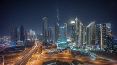Dubai şehir merkezinin havadan panoramik görüntüsü gece saatlerinde aydınlatılmış pek çok kulenin olduğu gökyüzü. Şehir merkezinde trafik var. Gökdelen ve yüksek binalar yukarıdan gelen ışığı kapatıyor, BAE.