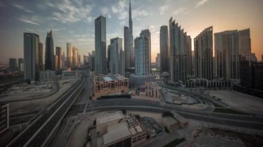 Gün doğumunda Dubai şehir merkezinin gökyüzü görüntüsü ve birçok zaman kulesi. Gökdelenler ve yüksek binalar arasındaki güneş ışınları, BAE. Akıllı kentsel şehirde iş alanı.