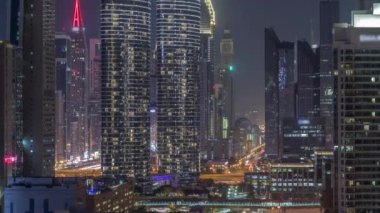 Dubai şehir merkezi ve finans bölgesindeki caddelerde trafik olan fütüristik kuleler ve aydınlık gökdelenler. Urban City Ufuk Çizgisi Hava Gecesi Zaman Çizgisi. Parlayan pencereler