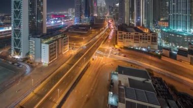 Fütürist kuleleri ve aydınlatılmış gökdelenleri olan hızlı karayolu kavşağı. Dubai şehir merkezi ve finans bölgesinde trafik vardı. Şehir silueti gökyüzü gece zaman çizelgesi yukarıdan.