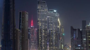 Dubai şehir merkezi ve finans bölgesinde pencereleri ışıklandırılmış fütüristik kuleler ve aydınlık gökdelenler. Urban City Ufuk Çizgisi Hava Gecesi Zaman Çizgisi. Karanlık gökyüzü