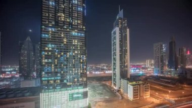 Dubai şehir merkezi ve finans bölgesinde karayolu trafiği olan fütüristik kulelerin panoramik manzarası ve aydınlatılmış gökdelenler. Urban City Ufuk Çizgisi Hava Gecesi Zaman Çizgisi. Ay batıyor