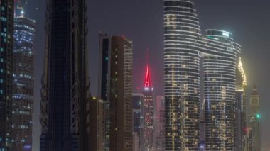 Dubai şehir merkezi ve finans bölgesinde parlayan ışıkları olan fütüristik kulelerin ve aydınlık gökdelenlerin tepesinde. Urban City Ufuk Çizgisi Hava Gecesi Zaman Çizgisi. Vinçli inşaat alanı