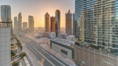 Günbatımında modern mimari zaman çizelgesi olan Business Bay District ufuk çizgisi. Ana karayolu yakınlarındaki Dubai gökdelenleri ve kulelerinin havadan panoramik görüntüsü. Kavşakta trafik vardı.