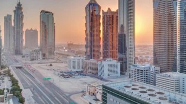 Günbatımında modern mimari zaman çizelgesi olan Business Bay District ufuk çizgisi. Ana karayolu yakınlarındaki Dubai gökdelenlerinin ve kulelerinin havadan görüntüsü. Kavşakta trafik vardı.