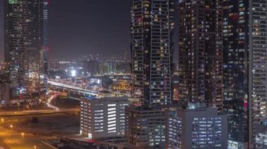 Modern mimari zaman çizelgesi olan Business Bay bölgesi ufuk çizgisi. Dubai gökdelenlerinin hava manzarası ve ana karayolu yakınında parlayan pencereleri olan aydınlık kuleler. Yol ayrımında trafik