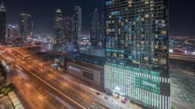 Panorama, gökyüzünden modern mimari zaman çizelgesiyle Business Bay semtinin ufuk çizgisini gösteriyor. Dubai gökdelenleri ve ana karayolu yakınlarındaki aydınlık kulelerin havadan görüntüsü. Kavşakta trafik vardı.