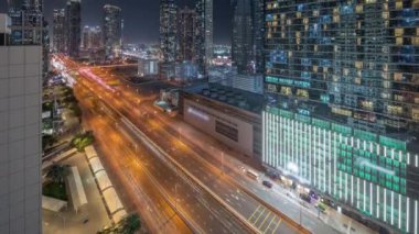 Business Bay semti panoramik gökyüzü modern mimari zaman çizelgesi ile dolu. Dubai gökdelenleri ve ana karayolu yakınlarındaki aydınlık kulelerin havadan görüntüsü. Kavşakta trafik vardı.