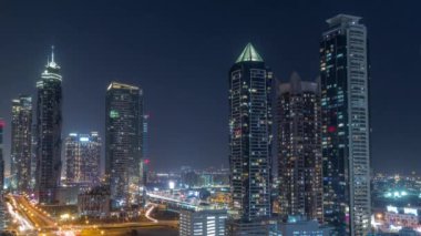 Modern mimari zaman çizelgesine sahip Business Bay semti ufuk çizgisi tüm gece boyunca yukarıdan devam edecek. Dubai gökdelenlerinin göz kırpan pencereleri ve ana karayolu yakınlarındaki aydınlatma kuleleri.