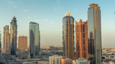 Business Bay semtinin ufuk çizgisi modern mimari ile sabah saatleri yukarıdan geliyor. Güneş doğarken Dubai gökdelenlerinin ve ana karayolu yakınlarındaki kulelerin havadan görüntüsü. Yol ayrımında trafik ve uzun gölgeler